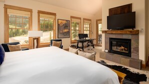 Une chambre spacieuse avec un grand lit, une cheminée, une télévision et un bureau équipé d’un ordinateur.