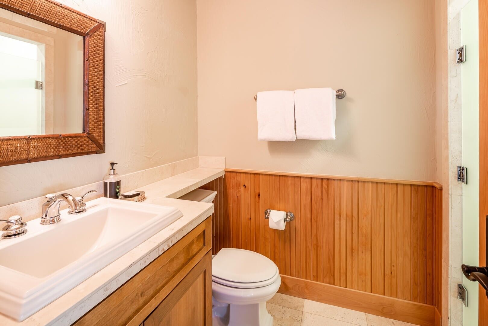A bathroom with a wooden vanity, a sink, a toilet, and a towel rack.