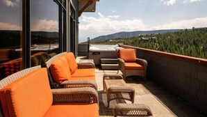 Une terrasse sur le toit aménagée avec des meubles en osier, un jacuzzi et une vue panoramique sur les montagnes.