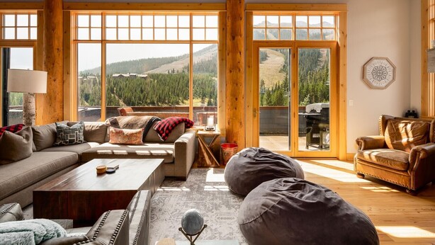 Un salon spacieux doté d’une grande fenêtre offrant une vue sur les montagnes, d’un canapé confortable, d’un fauteuil en cuir et d’une table basse.