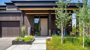 Uma casa moderna com uma garagem grande, um alpendre coberto e um jardim bem cuidado.