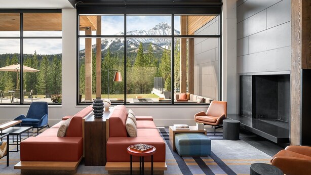 A modern living room with large windows, a fireplace, and a view of mountains. - 215 Lakelodge 2 Bedroom Condo by Moonlight Basin Lodging (Big Sky)