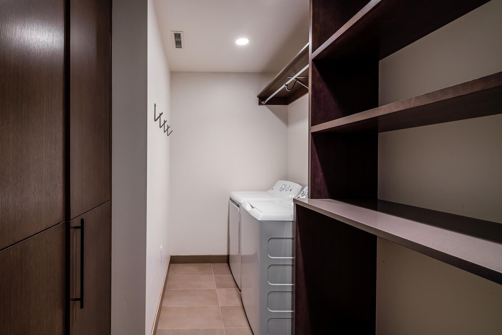 Une buanderie équipée d’un lave-linge, d’un étendoir et d’une armoire en bois.