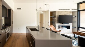 A modern kitchen with a large island, built-in appliances, and a stone accent wall. - 221 Lakelodge 2 Bedroom Condo by Moonlight Basin Lodging (Big Sky)