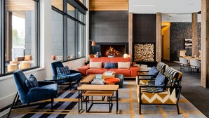 A modern living room with a fireplace, large windows, and a cozy seating area with sofas and chairs. - 221 Lakelodge 2 Bedroom Condo by Moonlight Basin Lodging (Big Sky)