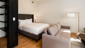 A modern hotel room with a bed, a sofa, a floor lamp, and a staircase. - 223 Lakelodge 1 Bedroom Condo by Moonlight Basin Lodging (Big Sky)