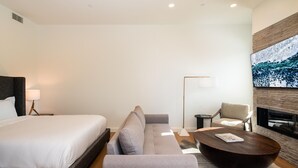 A modern hotel room with a large bed, a sofa, a coffee table, and a TV mounted on the wall. - 223 Lakelodge 1 Bedroom Condo by Moonlight Basin Lodging (Big Sky)