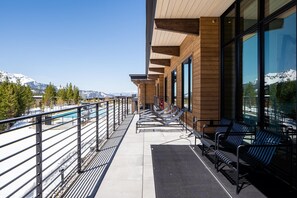 A balcony with a view of a mountain range, a pool, and seating areas. - 232 Lakelodge 3 Bedroom Condo by Moonlight Basin Lodging (Big Sky)