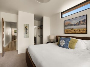 Une chambre à coucher avec un lit, un tableau, une lampe et une vue sur un paysage montagneux.