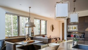 A modern kitchen with a central island, large windows, and a dining area with a bench. - 8 Alpine Bend 3 Bedroom Home by Moonlight Basin Lodging (Big Sky)