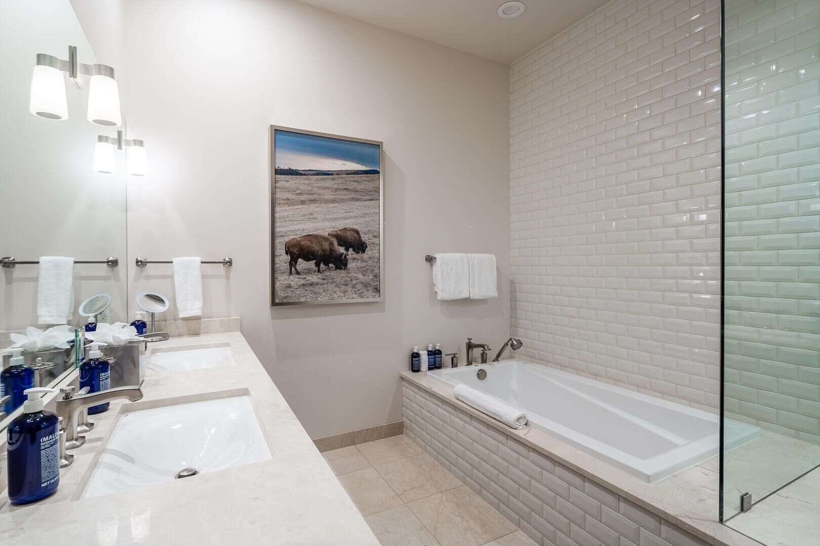 Un baño moderno con dos lavamanos, una bañera grande y un recinto de ducha de vidrio.