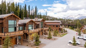 A row of log cabin-style buildings with balconies, surrounded by trees and a mountain backdrop. - 4b Lodgeside 3 Bedroom Townhouse by Moonlight Basin Lodging (Big Sky)