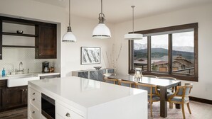 A modern kitchen with a central island, dark wooden cabinets, white countertops, and pendant lighting. - 4b Lodgeside 3 Bedroom Townhouse by Moonlight Basin Lodging (Big Sky)