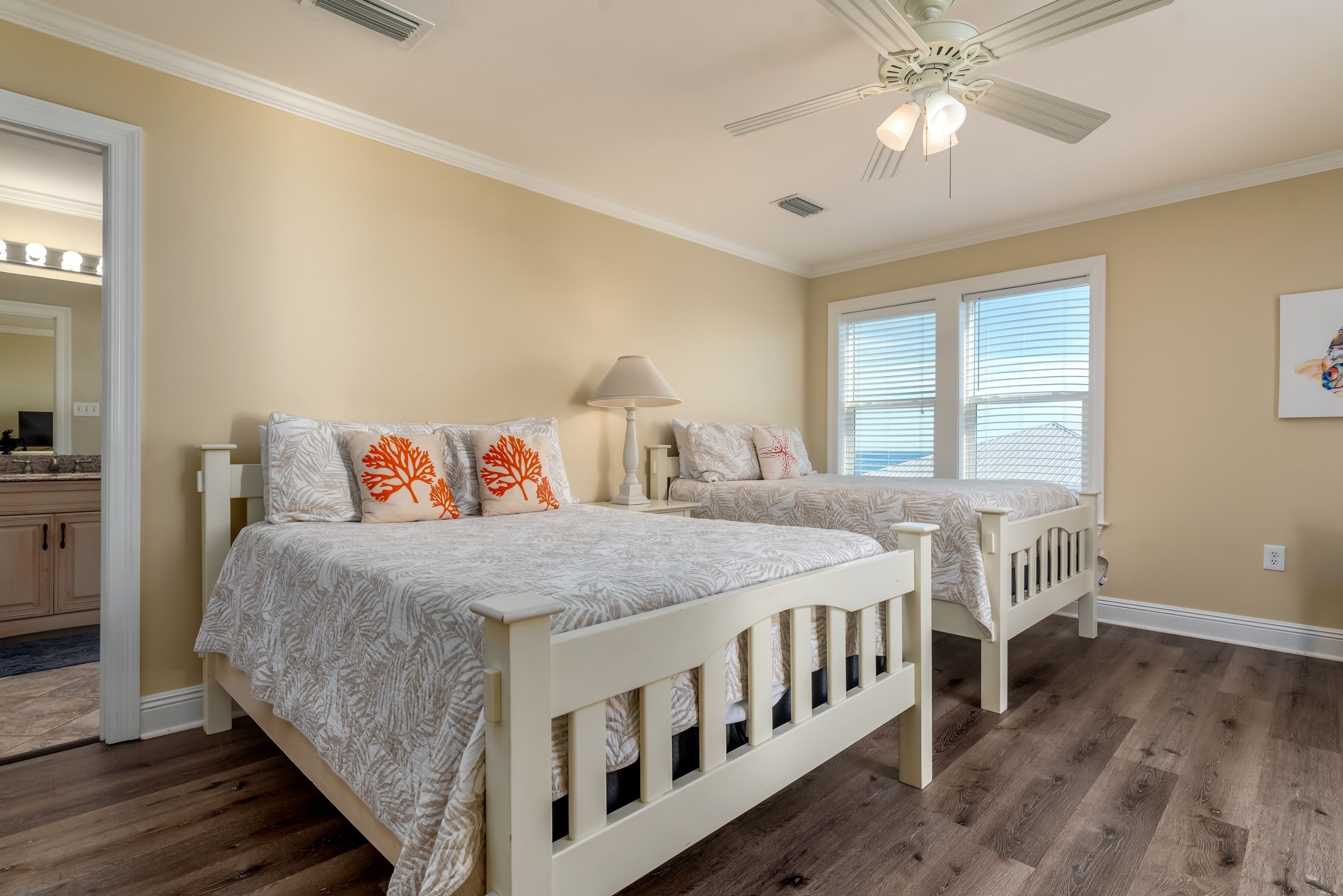 A bedroom with two beds, a ceiling fan, and a window with blinds.