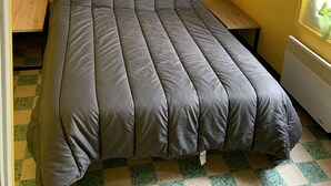 Une chambre avec un lit, deux lampes de chevet, une petite table et un radiateur.