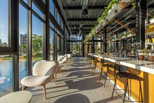Un área de bar moderna con una barra larga, taburetes y vistas a una piscina a través de amplios ventanales.