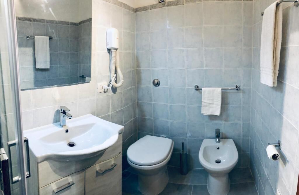 A compact bathroom with a sink, toilet, bidet, and a towel rack.