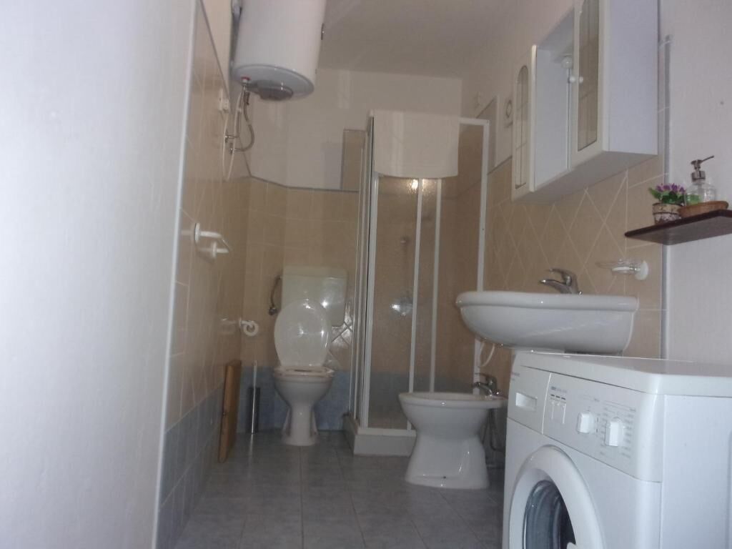 Une petite salle de bain comprenant des toilettes, un bidet et un lave-linge.