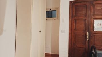 A hallway with a wooden door, a window, and a doorbell.