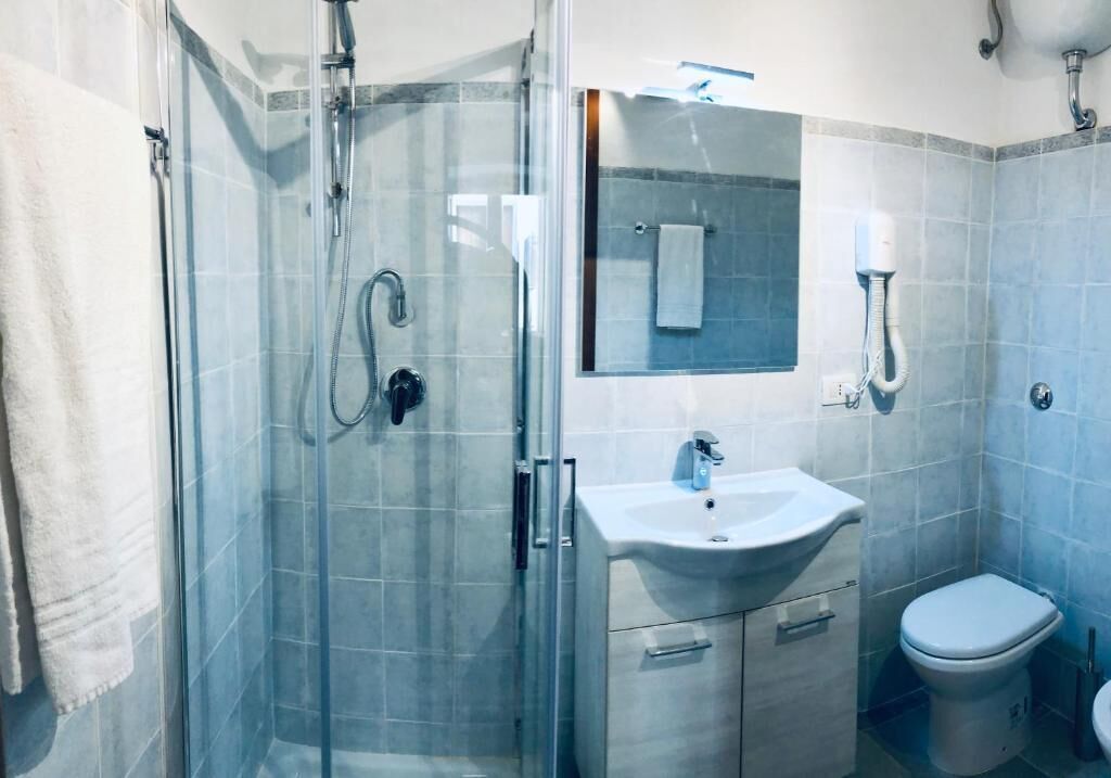 Een moderne badkamer met een douchecabine van glas, een wastafel en een toilet.