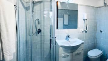Een moderne badkamer met een douchecabine van glas, een wastafel en een toilet.