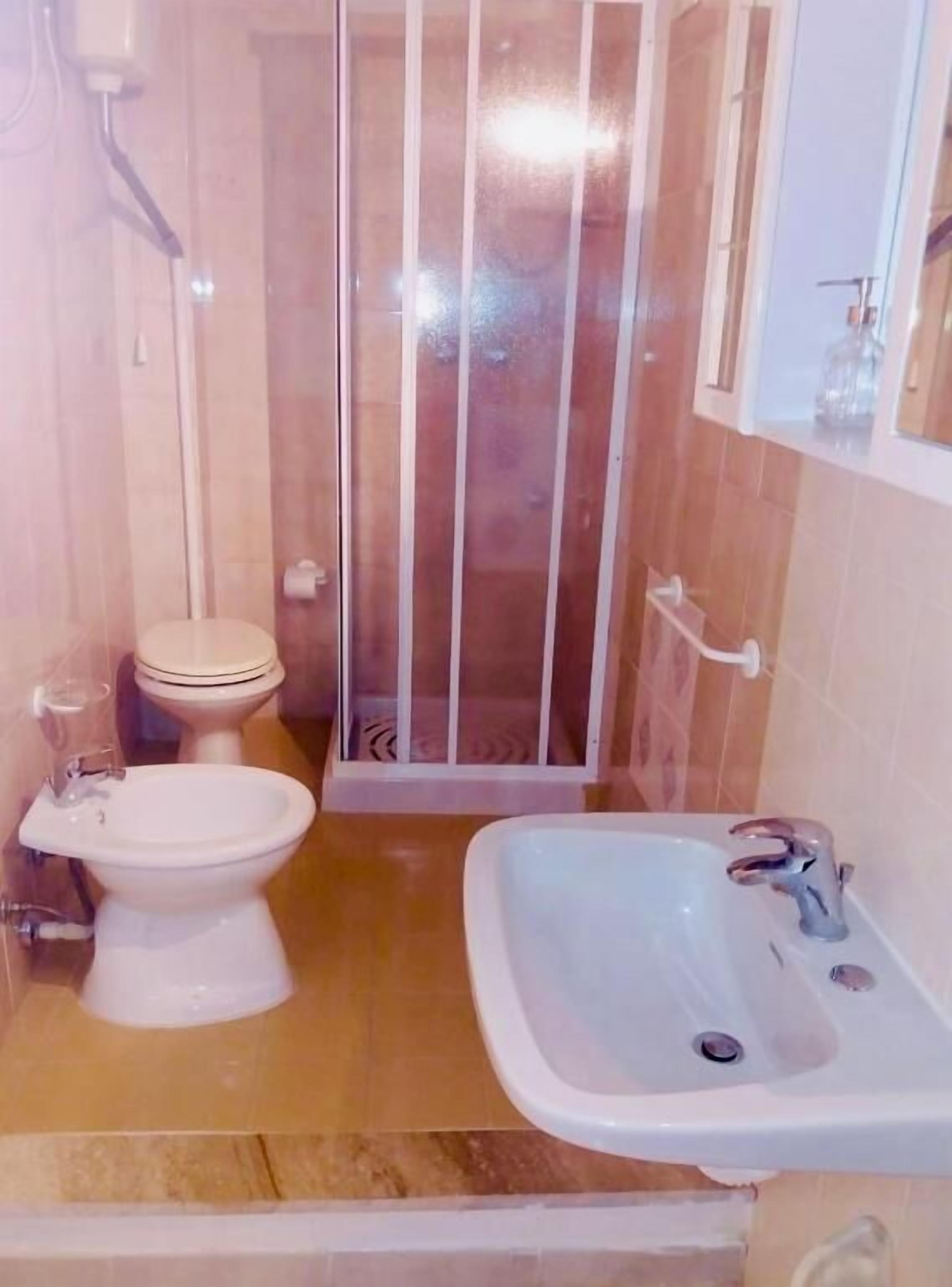 Baño con inodoro, bidé, cabina de ducha y lavamanos.