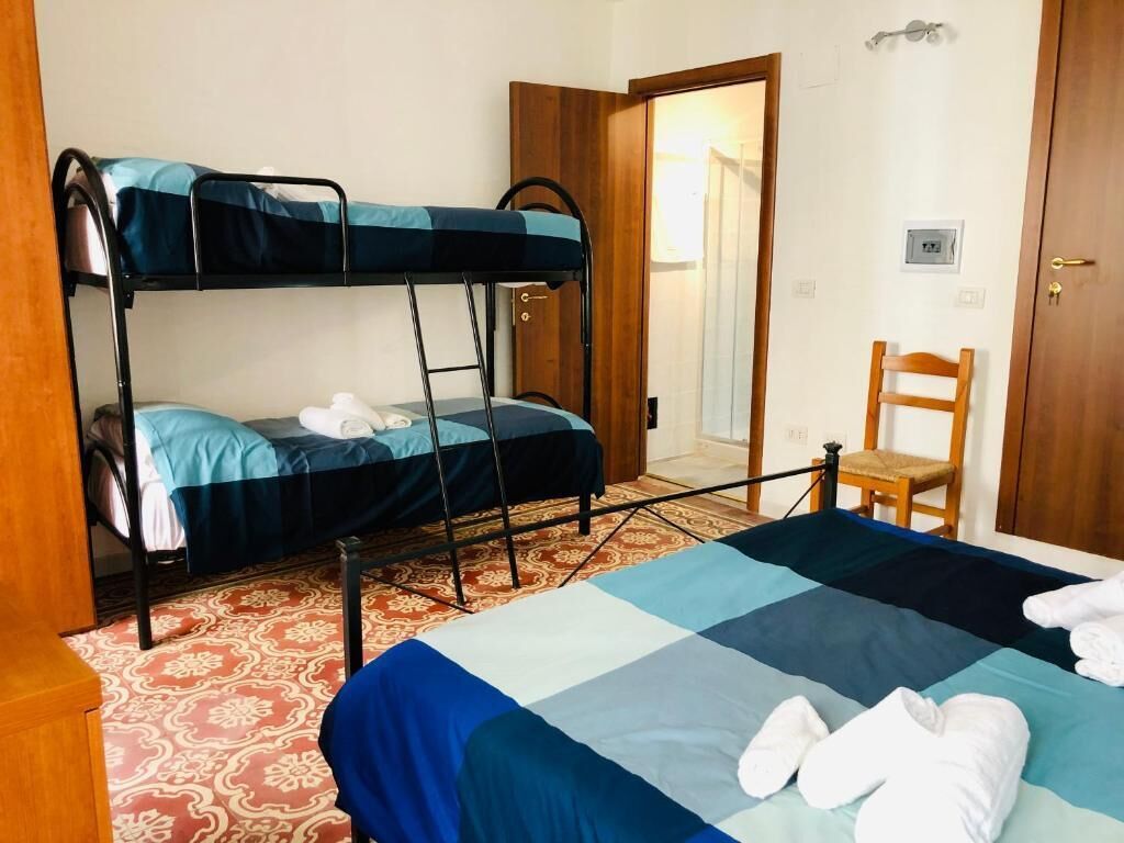 Una habitación con literas, una cama individual, una silla y una puerta.