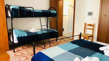Una habitación con literas, una cama individual, una silla y una puerta.