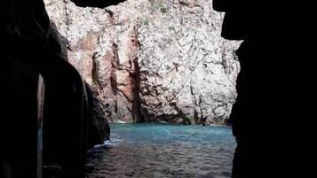 A rocky coastal cave entrance with clear blue water.