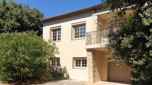 A two-story house with a balcony, stone pillars, and a garage. - Au Calme, Très Jolie Maison, bel Espace Piscine, Pool House, Cadre Champêtre (Cadenet)