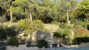 A stone wall with a bench, surrounded by various shrubs and trees. - Au Calme, Très Jolie Maison, bel Espace Piscine, Pool House, Cadre Champêtre (Cadenet)