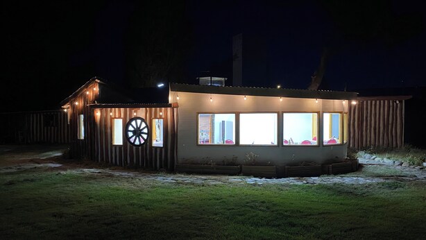 A small, single-story building with a sloped roof, large windows, and a wheel feature on the side. - Patagonia Bordelago (Río Ibáñez)