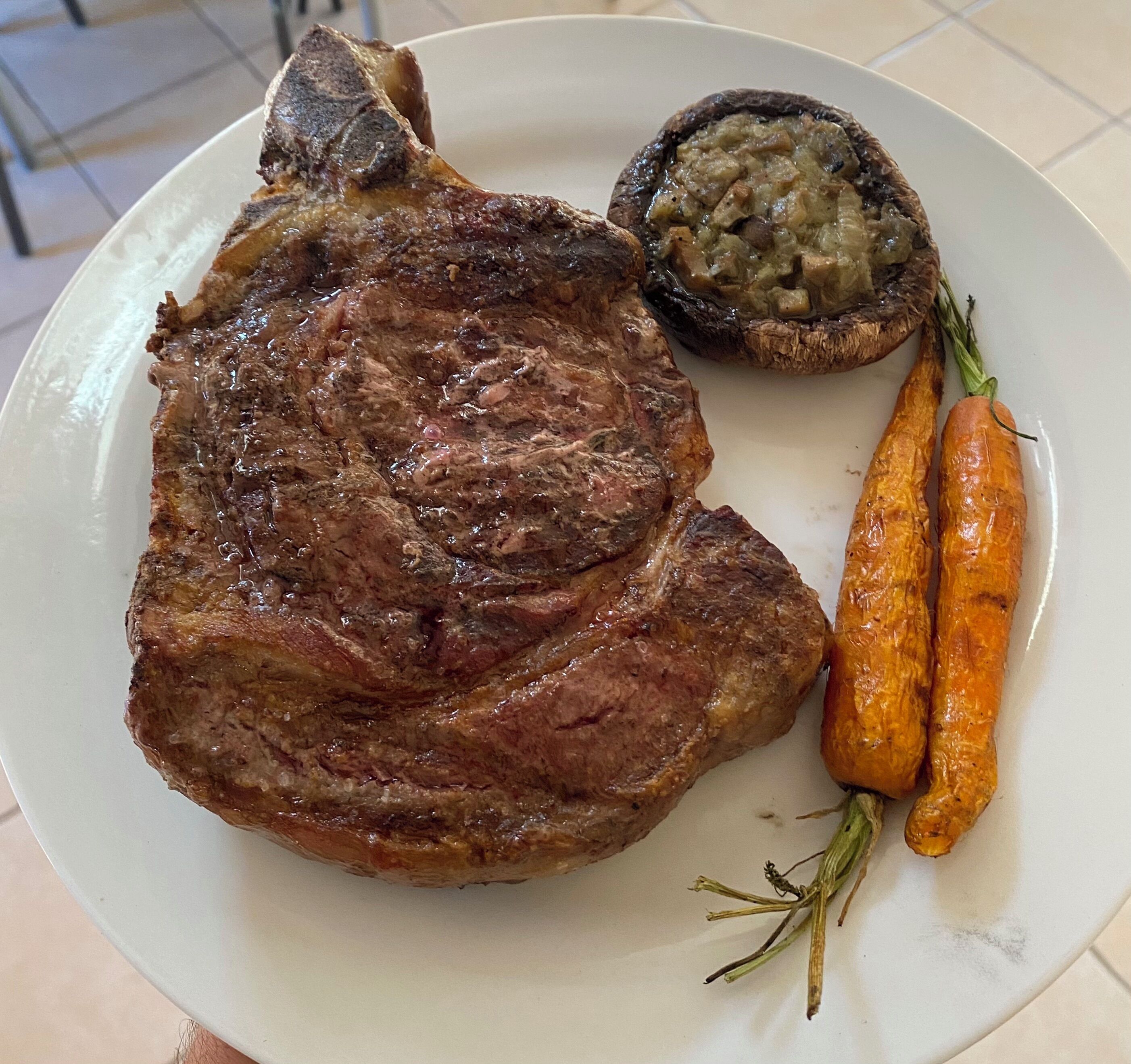 Un plato con un bistec, una papa al horno y dos zanahorias.