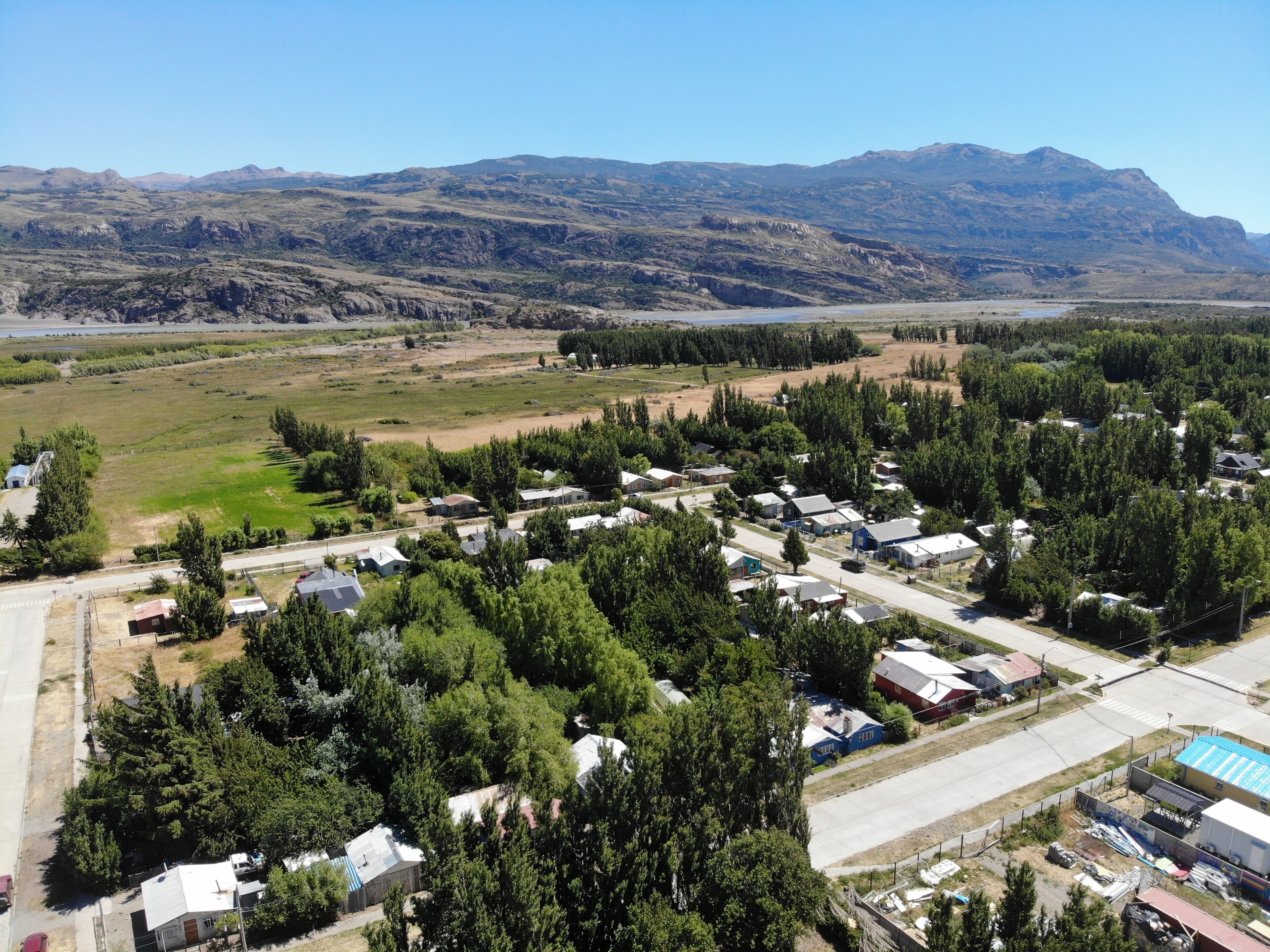 A small town with residential houses, a main road, and a river in the background.