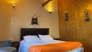A hotel room with a bed, a nightstand, a chair, and a wooden wall with a woven tapestry. - Patagonia Bordelago (Río Ibáñez)