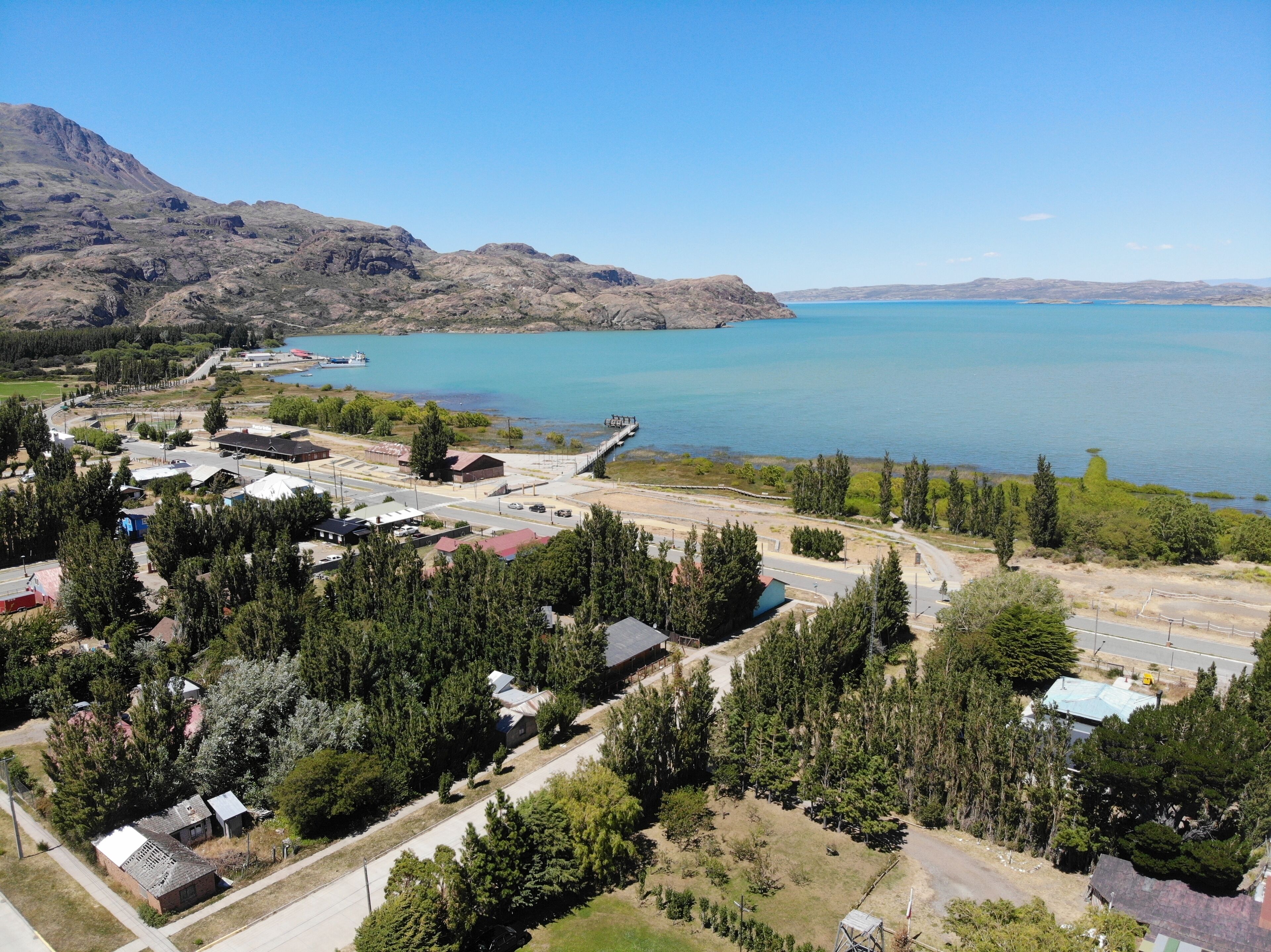 A coastal town with a marina, residential buildings, and a mountainous backdrop.