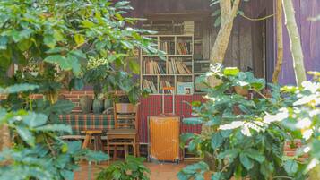 A rustic outdoor seating area with a wooden table and chairs, surrounded by greenery.