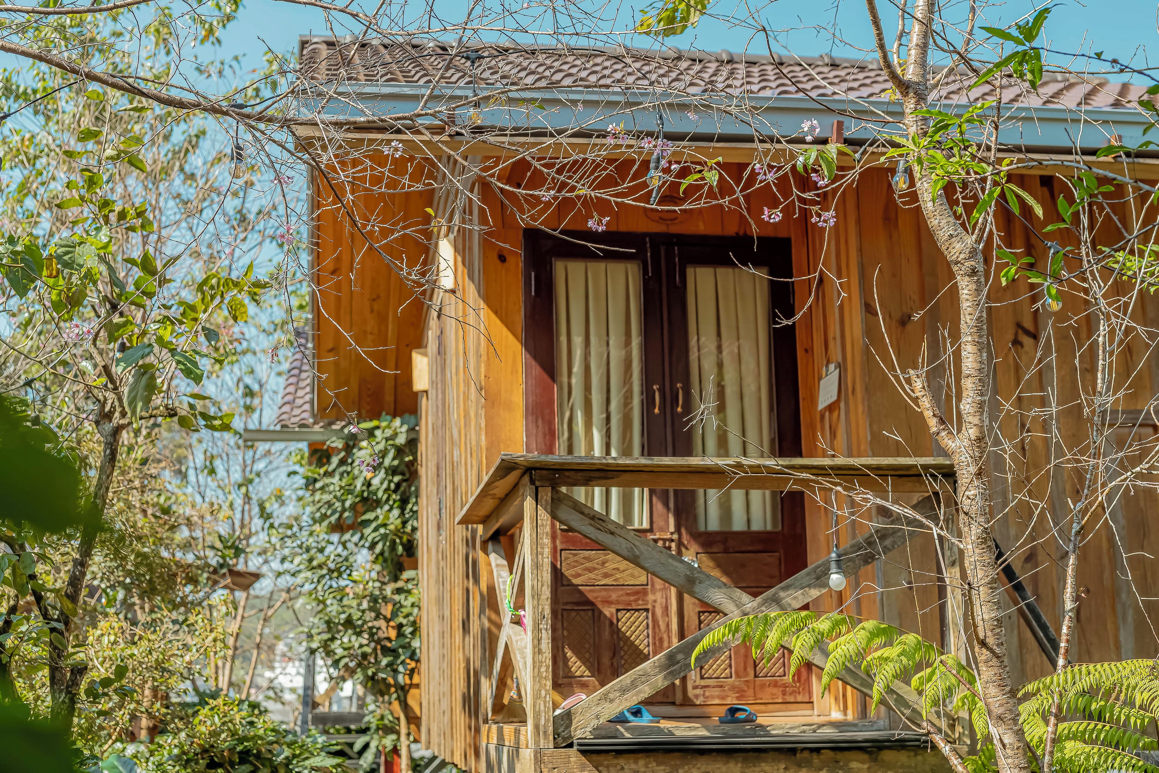 Een houten chalet met een balkon, een deur en een raam.
