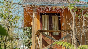 Een houten chalet met een balkon, een deur en een raam.
