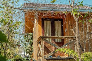 A wooden cabin with a balcony, a door, and a window.