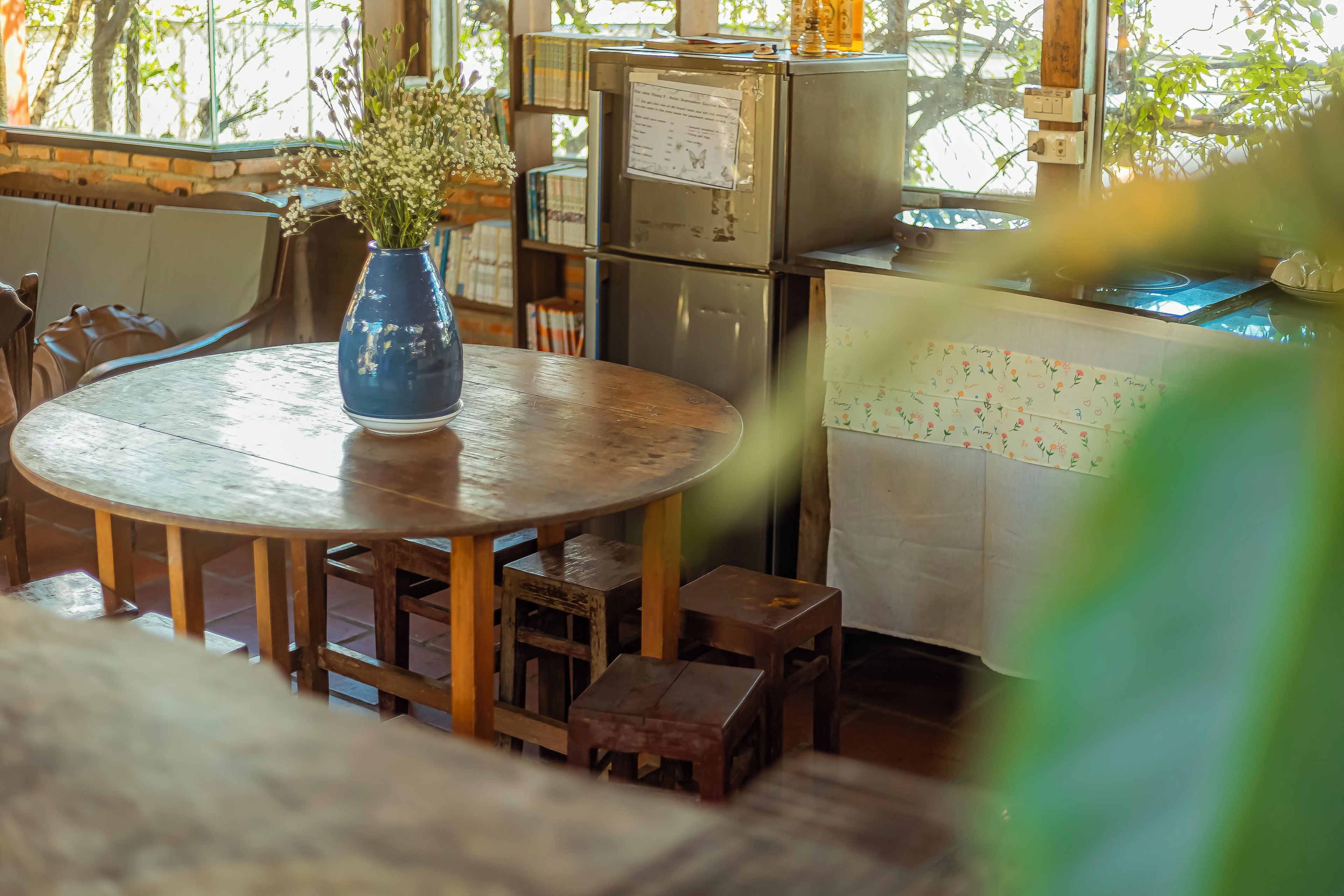 A room with a round wooden table, a vase with flowers, and a cabinet with papers.