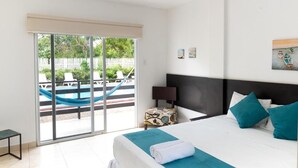 Un dormitorio con una cama grande, una mesita de noche, una silla y vistas a una piscina y zona de estar exterior.
