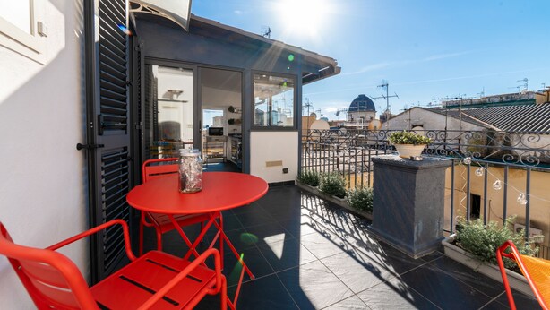 A balcony with red chairs and a small table, a clear view of the cityscape, and a building with a dome in the background. - Purgatorio Terrace - One Bedroom Apartment, Sleeps 2 (Naples)