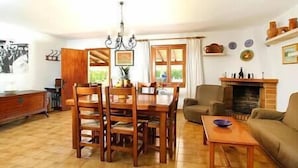 A cozy living room with a dining area, a fireplace, and a large window. - Villa Paparri, Lovely 3 bedroom villa close to Pollensa (Pollença)