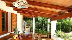 A wooden dining area with a table set for a meal, surrounded by potted plants and a view of a lush garden. - Villa Paparri, Lovely 3 bedroom villa close to Pollensa (Pollença)