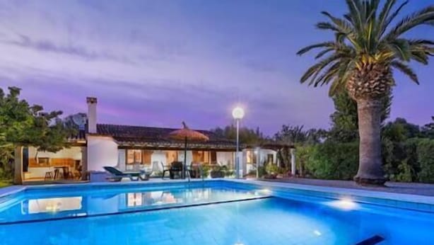 A swimming pool with lounge chairs and a palm tree, surrounded by a building with a tiled roof. - Villa Paparri, Lovely 3 bedroom villa close to Pollensa (Pollença)