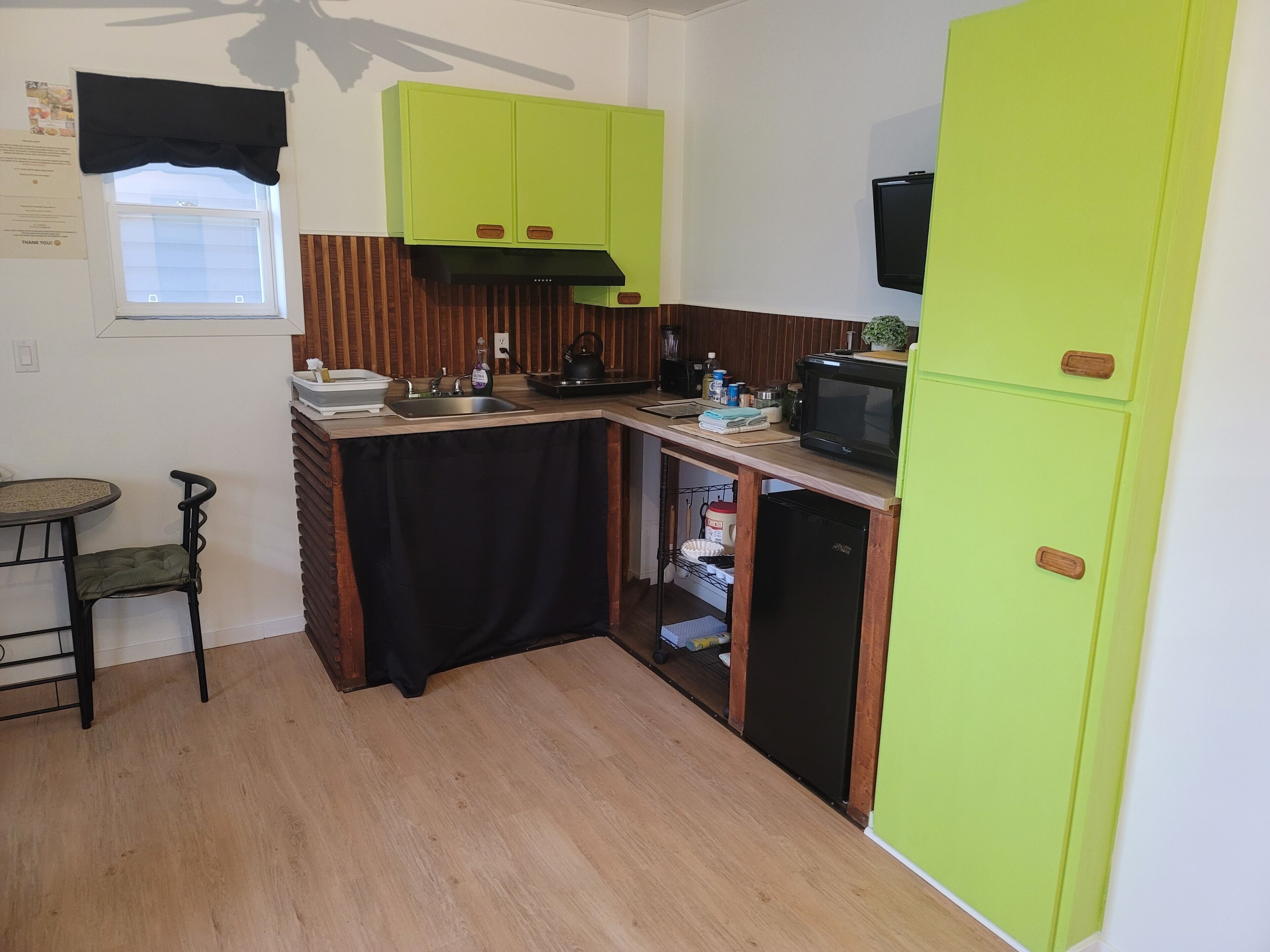 A compact kitchen with a sink, stove, and green cabinets.