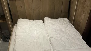 A bed with white bedding and an orange zipper.