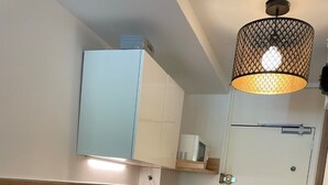 A compact kitchen with a wooden countertop, a built-in dishwasher, a coffee maker, and a hanging light fixture.