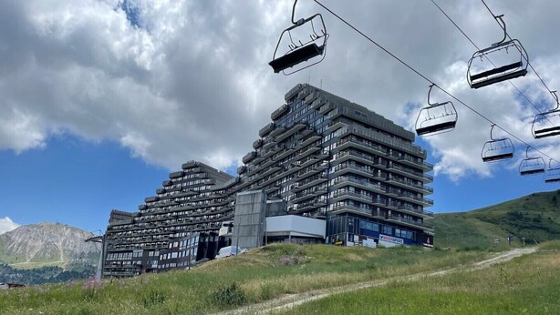 A modern multi-story building with a ski lift in the foreground.